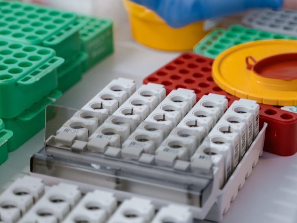 Gloved hands handling laboratory sample racks